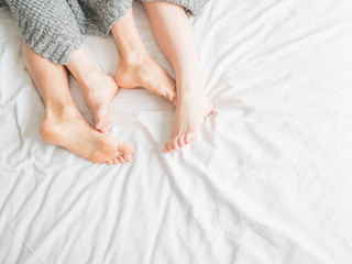 Feet of a couple under blanket. Close up view. Love, rest and relationship concept