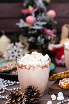 Hot cocoa with marshmallows and cinnamon in glass on the table in Christmas decorations
