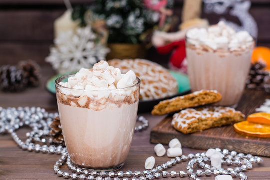 Hot cocoa with marshmallows and cinnamon in glasses on the table in Christmas decorations