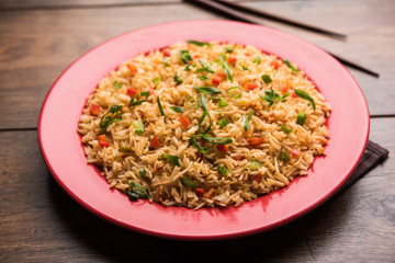 Schezwan Fried Rice Masala is a popular indo-chinese food served in a plate or bowl with chopsticks. selective focus