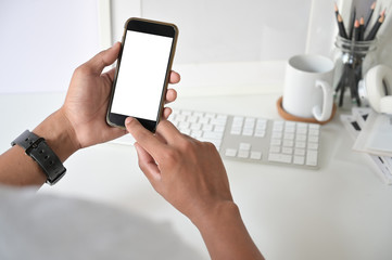 Fototapeta na wymiar Mockup smartphone on man hands empty display with office desk background.
