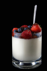 Panakota creamy Italian dessert in a glass cup with berries and a spoon