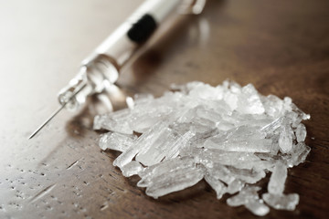 Hard crystal drugs and prohibited substances, syringes, cooked heroine spoon on brown table. close up image on substances. Drug abuse and addiction concept. International Day against drug abuse