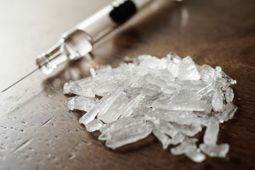 Hard crystal drugs and prohibited substances, syringes, cooked heroine spoon on brown table. close up image on substances. Drug abuse and addiction concept. International Day against drug abuse