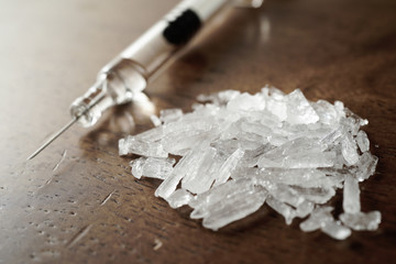 Hard crystal drugs and prohibited substances, syringes, cooked heroine spoon on brown table. close up image on substances. Drug abuse and addiction concept. International Day against drug abuse