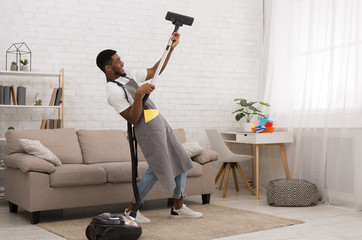 Young man cleaning house with vacuum cleaner