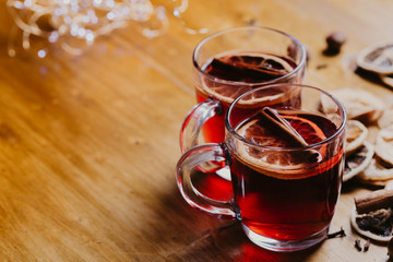 Mulled wine in mugs with scarf on wooden table.