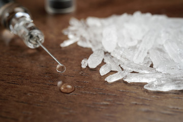 Hard crystal drugs and prohibited substances, syringes, cooked heroine spoon on brown table. close up image on substances. Drug abuse and addiction concept. International Day against drug abuse