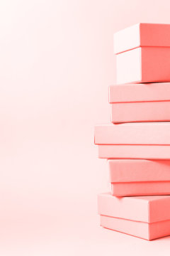Close view the stack of boxes, lying on each other on living coral color pastel background. Gift festive selection.