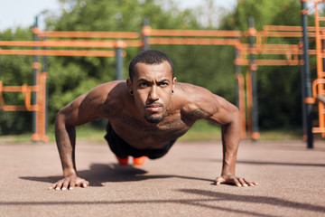 Obraz premium Shirtless african-american man doing push ups outdoors