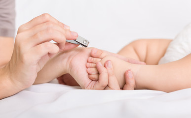 Obraz na płótnie Canvas Mother cutting toenails for Baby close up