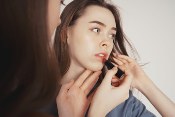 Two sisters twins beautiful girls in casual painting lips doing