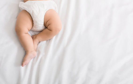 Baby legs and bottom in diaper on bed Photos | Adobe Stock