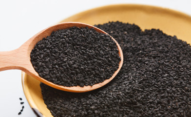 Black cumin seeds in wooden bowl and spoon