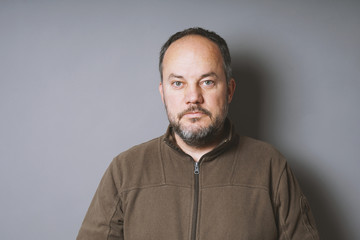 Fototapeta premium middle aged man in his 40s with short dark hair and graying beard against gray wall with copy space