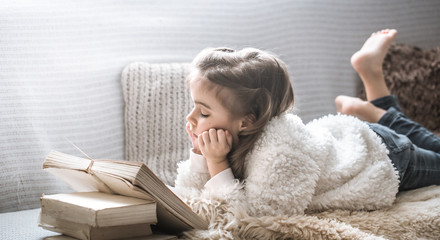 little girl reading a book on a comfortable sofa, beautiful emotions