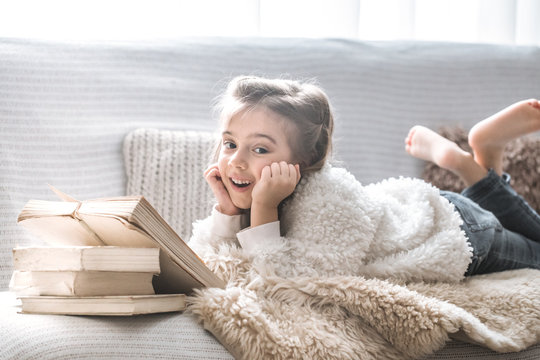 little girl reading a book on a comfortable sofa, beautiful emotions