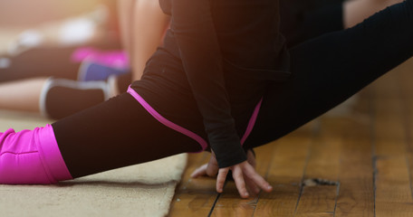 Young female athlete at a fitness room working out on side split. Flexible athletic girl doing stretching on the splits in the gym
