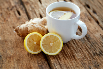 Cup of ginger tea with lemon on wooden