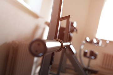 Close up of a black empty barbell bar in the gym. Barbell bar without plates on the rack in the gym club. Vertical weight lifting equipment.