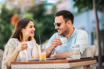 Beautiful loving couple sitting in a cafe enjoying in coffee and conversation, selective focus