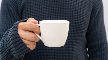 Man holding a white cup of coffee.