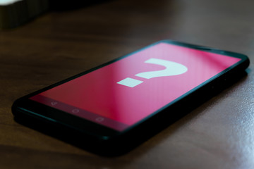 Black smartphone with a question mark on the screen