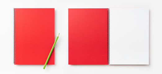 Top view of  red spiral notebook, page, pencil