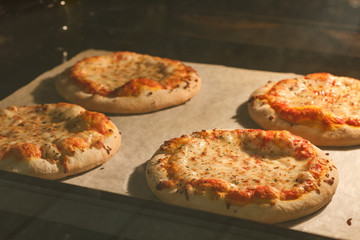Four little pizza margherita with tomato sauce and mozzarella baking in the electric oven