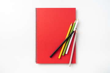 Top view of  red spiral notebook, page, pencil