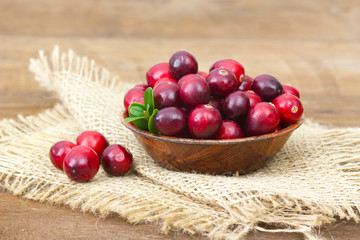 Cranberries in a bowl on wooden background.