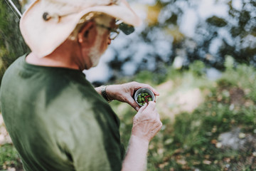 Close up of a pleasant elderly fisherman holding baits while fishing on the weekend