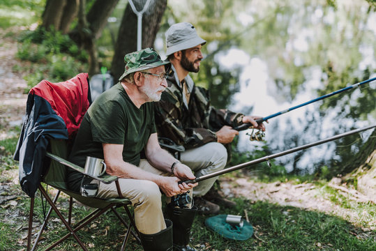 Aged man fishing with his son on the river bank