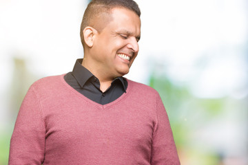 Middle age arab man over isolated background looking away to side with smile on face, natural expression. Laughing confident.
