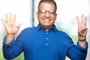 Naklejka premium Middle age arab man wearing glasses over isolated background showing and pointing up with fingers number eight while smiling confident and happy.