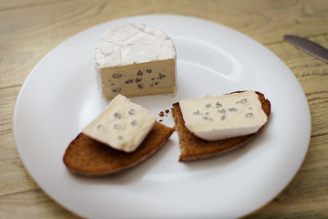 Black bread with blue cheese on a white plate.