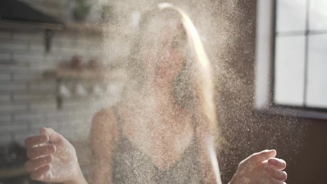 Young girl in bra with long hair clap her hands which is in wheat flour. Woman smiling and enjoying doing it. Slow motion.
