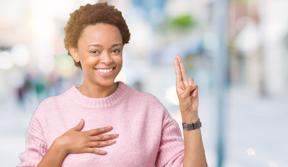 Beautiful young african american woman over isolated background Swearing with hand on chest and...