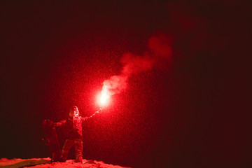 Snowboarder stands signal fire night