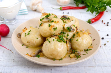 Ukrainian dumplings with meat and mushrooms in a bowl on a white background.