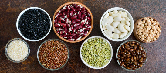 Healthy food, dieting, nutrition concept, vegan protein source. Assortment of colorful raw legumes: green peas, beans, chickpeas, rice in bowls. Banner.