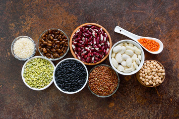 Healthy food, dieting, nutrition concept, vegan protein source. Assortment of colorful raw legumes: lentils, green peas, beans, chickpeas, rice in bowls. Background.
