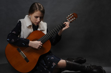 Fototapeta premium Girl with guitar. Studio light. Dark background.