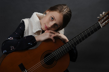 Fototapeta premium Girl with guitar. Studio light. Dark background.