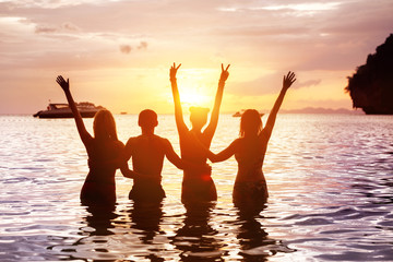 Four happy friends meeting sunset sea beach