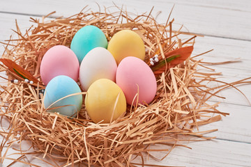 Easter background. Colorful easter eggs in paper nest on a white background, close up