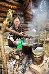 girl preparing food camping pots hanging over a campfire in a camping trip