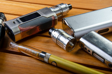 Popular vaping e cig devices mod.electronic cigarette over a wood background. vaporizer e-cig old...