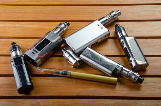 Popular vaping e cig devices mod.electronic cigarette over a wood background. vaporizer e-cig old device model. 