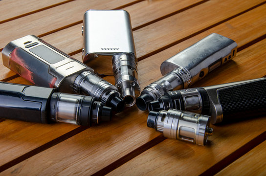 Popular vaping e cig devices mod.electronic cigarette over a wood background. vaporizer e-cig old device model. 